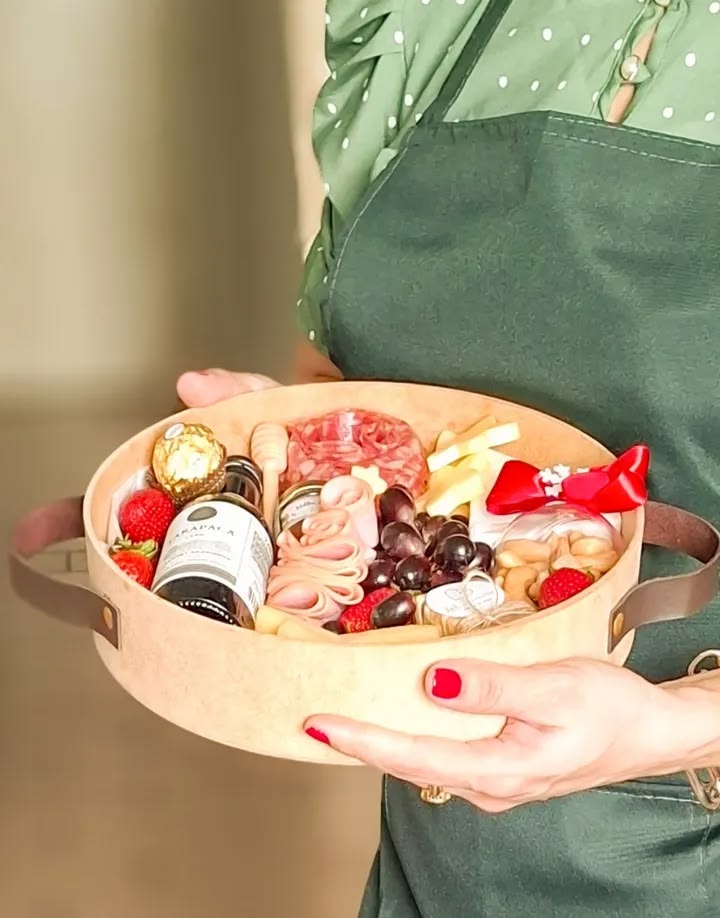 Mãos preparando arranjo de flores e doces em caixa